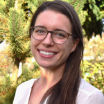 Photo of Bailey Wambold, volunteer coordinator, facing forward in front of a background of greenery.