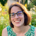 Sarah Pyle facing forward. She is in front of foliage.